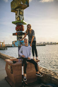 码头边彩色雕塑旁的欢笑情侣