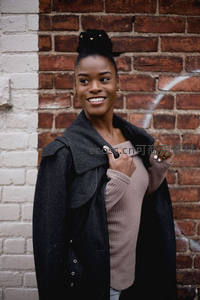 砖墙前微笑的时尚女性