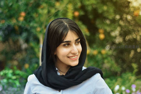 微笑女子头戴黑巾置身绿意盎然背景中