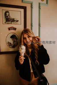 金发女郎手持冰淇淋，复古墙前留影