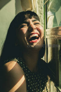 女子窗边开怀大笑，阳光洒落