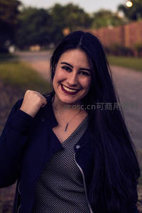 长发女子街边微笑，阳光洒落肩头