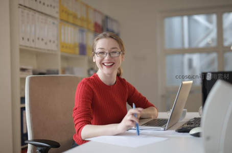 办公室内女子微笑书写专注工作