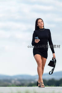 都市丽人手持手机漫步户外平台