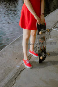 红裙少女持滑板静立水边