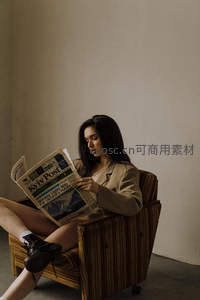 复古扶手椅中阅读报纸的女子
