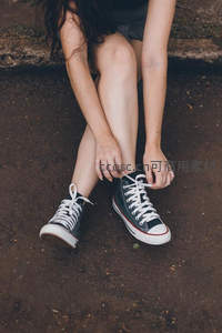 泥土路上系鞋带的帆布少女