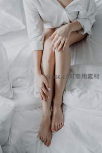 白衬衫女子轻抚双腿，展现柔美肌肤质感