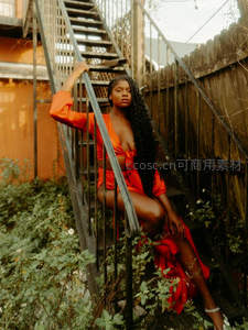 红裙女子倚靠铁梯绿植环绕