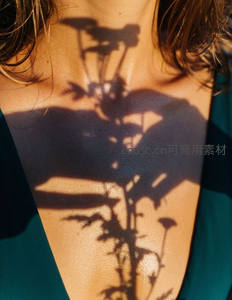 阳光投射植物阴影在女性锁骨上