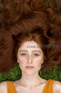 红发少女躺草地，蓝眸直视镜头