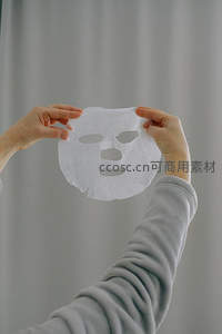 双手举起白色纸质面膜特写