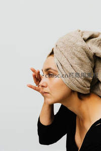 毛巾包头女子专注护肤侧脸特写