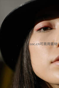 光影下的精致眼妆与黑色礼帽特写