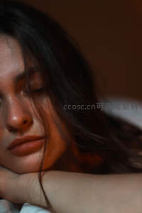 深色长发女子闭目枕臂安睡特写