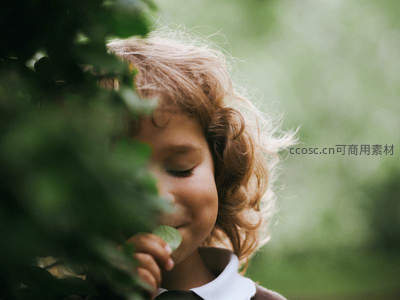绿叶丛中偷笑的卷发孩童