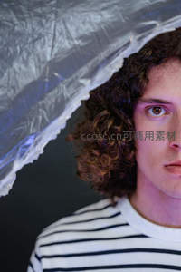 卷发青年透过塑料薄膜凝视镜头