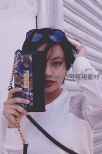 时尚女性手持蛇纹手袋街拍