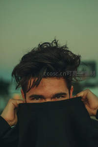 男子用衣领遮面，只露深邃双眸