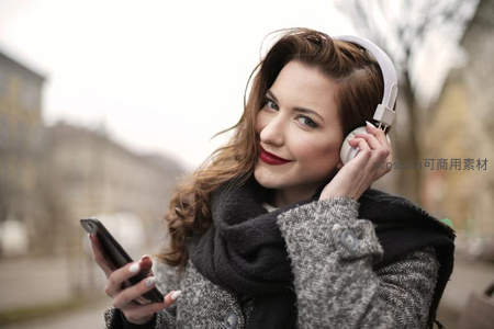 街头少女戴耳机微笑，享受音乐时光