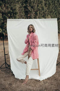 户外白色幕布前，粉衣女子优雅摆拍