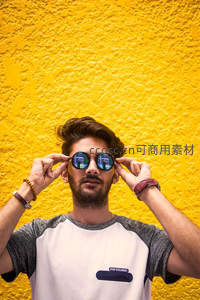 黄墙前戴墨镜的时尚青年
