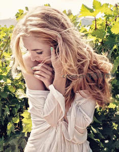 葡萄园中金发女子轻抚秀发的柔美瞬间
