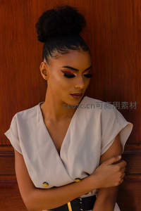 优雅女性倚靠木质背景凝视远方