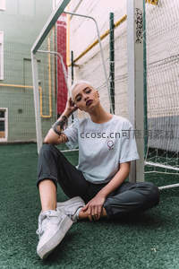 白发女子坐足球场边沉思凝望