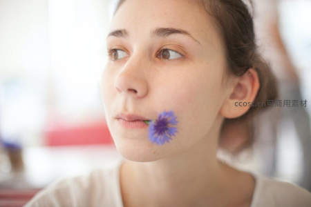 少女脸颊轻衔蓝花俏皮可爱