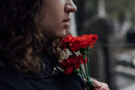 女子手捧红康乃馨静默追思