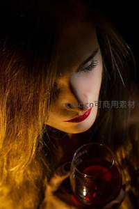 暖光红酒杯旁，红唇女子低头沉醉瞬间