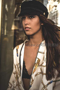街头时尚女郎戴帽回望，链条外套显个性