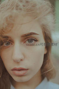 特写蓝眸少女，卷发柔光映衬清秀面容