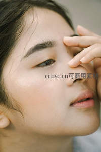 少女轻触眉间，侧脸展现细腻肌肤质感