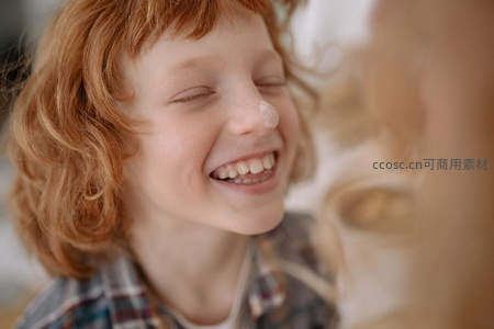 红发孩童闭眼大笑露出洁白牙齿