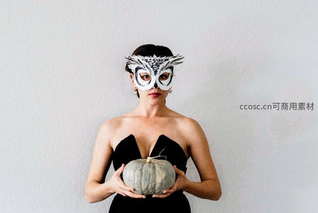 戴猫头鹰面具的女子手捧南瓜