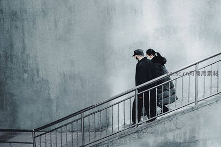 灰墙下戴口罩的行人缓步上楼