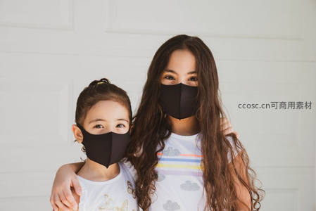 母女佩戴黑色口罩温馨相拥于白色背景前