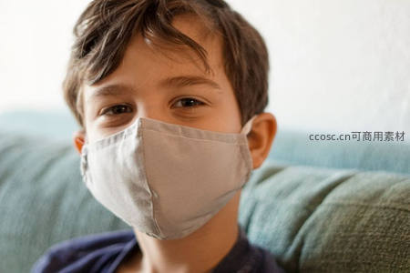 戴口罩的男孩坐在沙发上凝视镜头