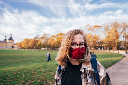秋日公园里戴红口罩的年轻女子