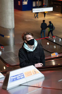 青年男子戴口罩乘地铁扶梯望向远方