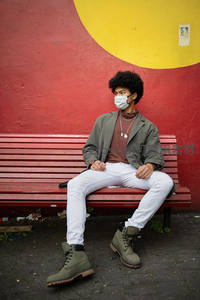 街头青年坐长椅戴口罩望远方