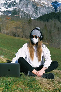 山野间戴口罩的女子与笔记本电脑