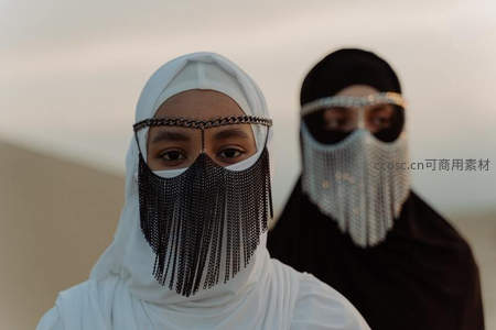 沙漠中两位身披链饰面纱的神秘女子