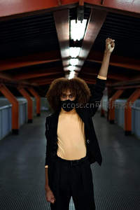 红廊下举拳的卷发青年，口罩遮面显力量