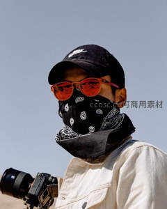 摄影师戴墨镜面巾持相机