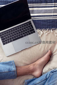 笔记本电脑置于床榻，赤足放松享受居家时光