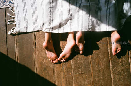 木质地板上四只赤足，阳光与阴影下的家庭温馨时刻
