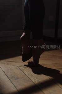 光影下的赤足舞步，木质地板映衬优雅身姿